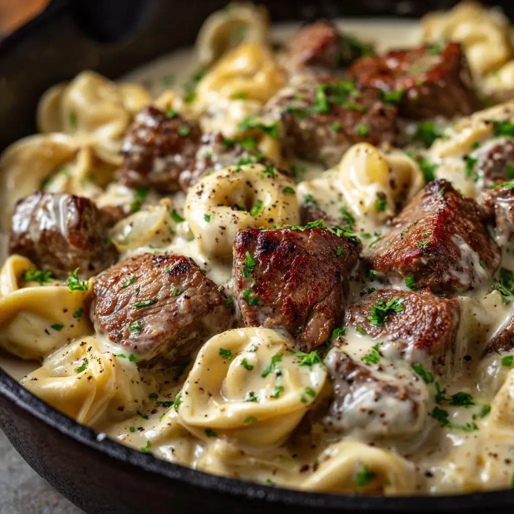 Garlic Steak Tortellini: A Restaurant-Quality Weeknight Dinner 1 A fork lifting a piece of garlic butter steak with cheese tortellini from a bowl, showcasing the finished dish ready to be eaten.