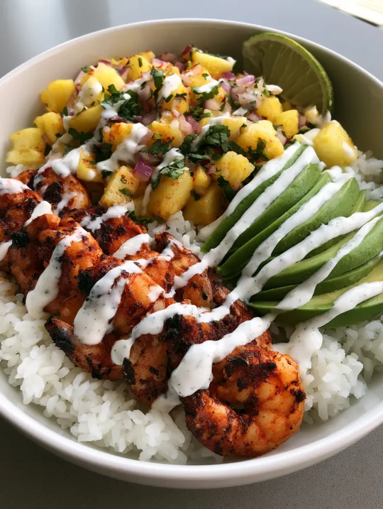 Professional plating of Pineapple Shrimp Rice Bowls with a thick white lime crema zig-zag drizzle and lime wedge.