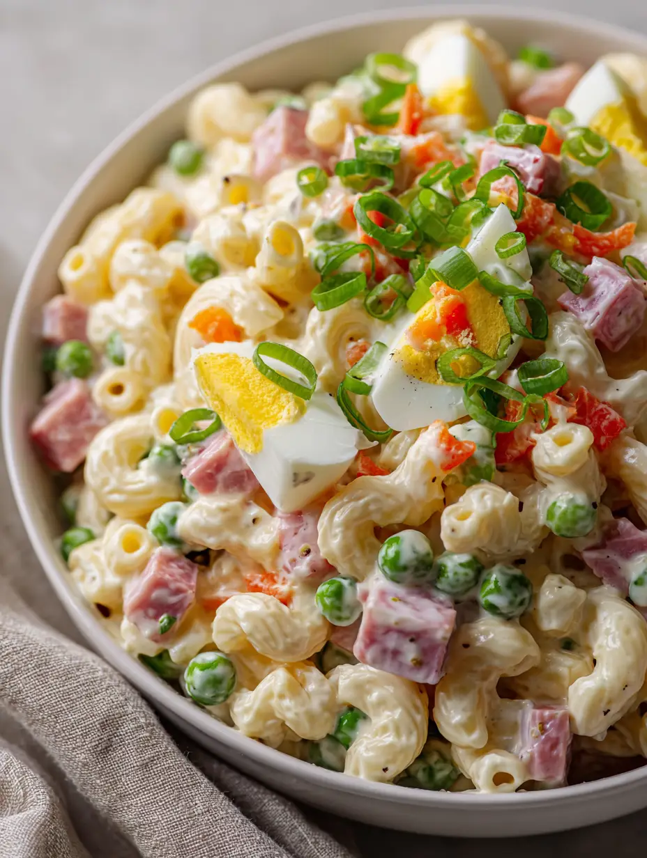 Close-up of Dolly Parton Macaroni Salad in a white bowl showing the thick velvety dressing and bright green peas.