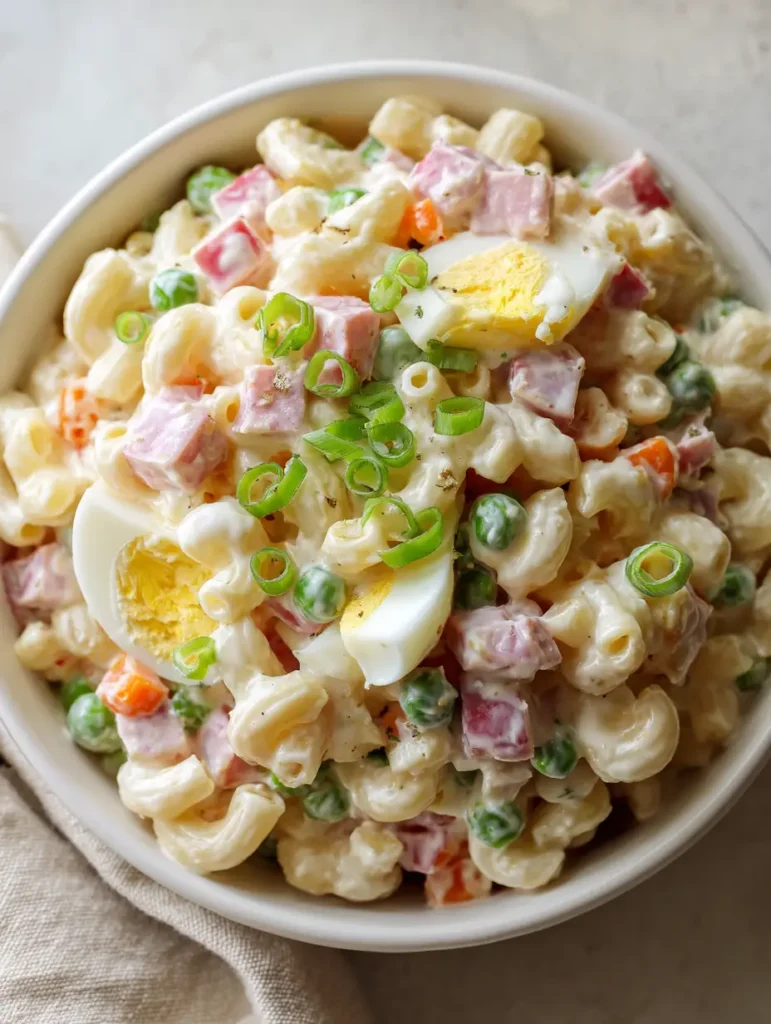A high-angle smartphone-style photo of Dolly Parton Macaroni Salad with pink ham cubes and diced eggs.