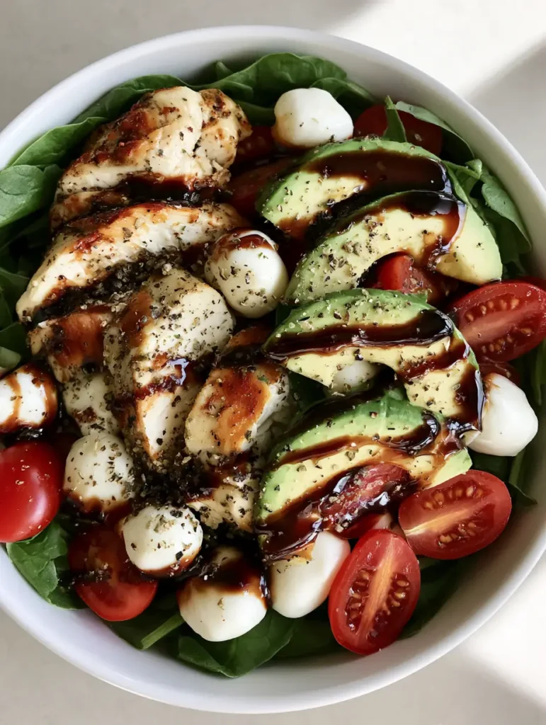 Close up of the glossy dark-brown balsamic glaze drizzled over a vibrant Baked Marinated Chicken Salad.