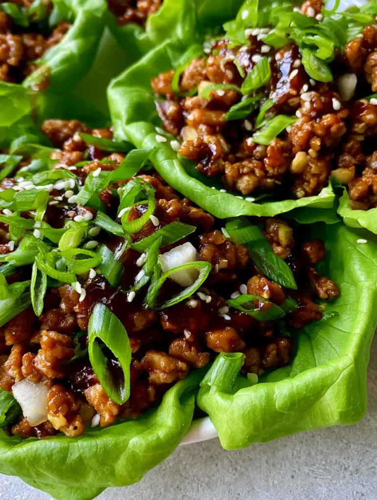 Vibrant butter lettuce cups filled with savory chicken, topped with scallions and sesame seeds. (PF Chang's Chicken Lettuce Wraps)