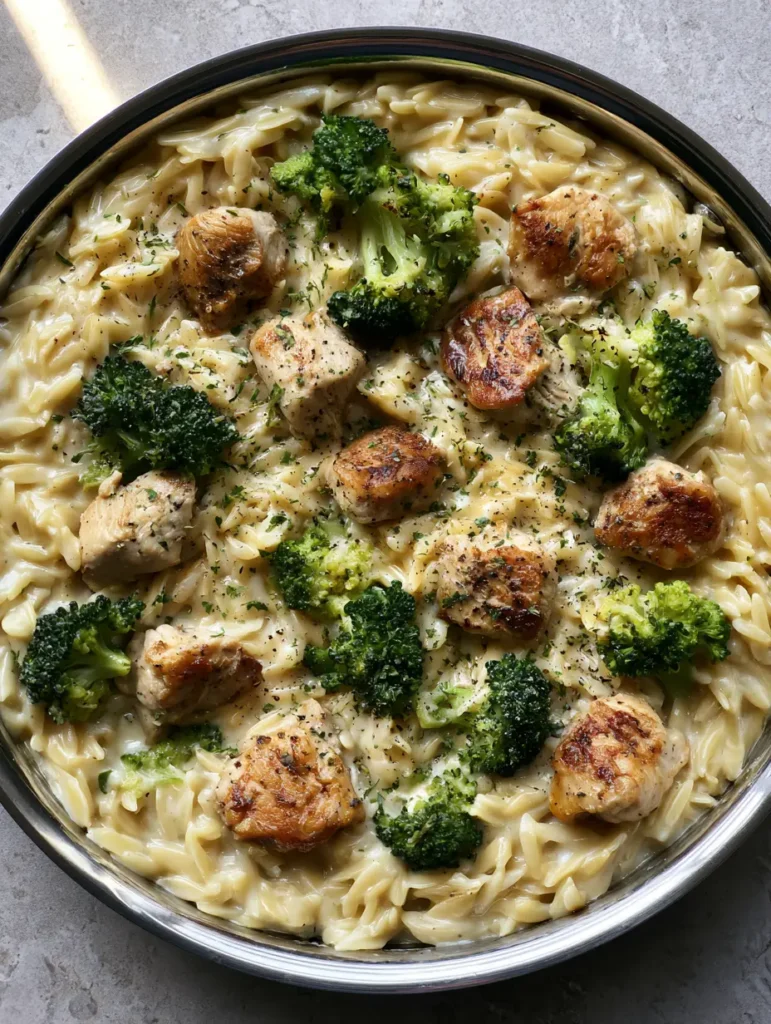 Authentic unedited photo of a metal skillet filled with Cheesy Chicken and Broccoli Orzo.