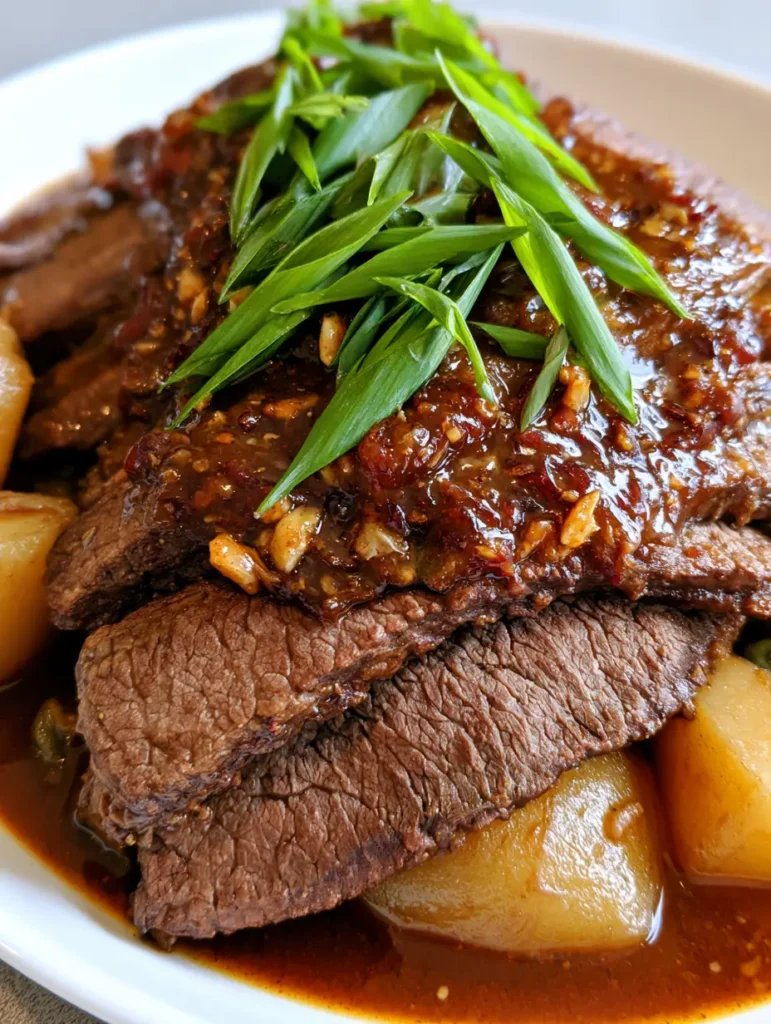 A side view showing golden potato chunks nestled in mahogany glaze next to braised brisket.