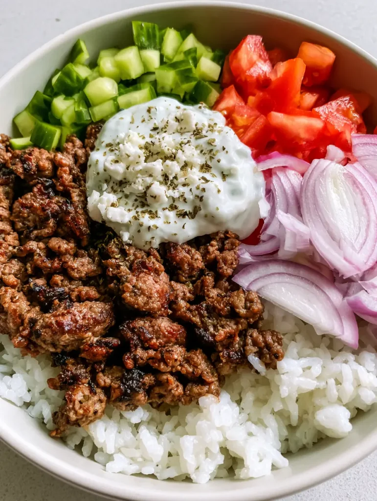Top-down view of assembled Greek Lamb Gyro Bowls showing the sectioned arrangement of ingredients.